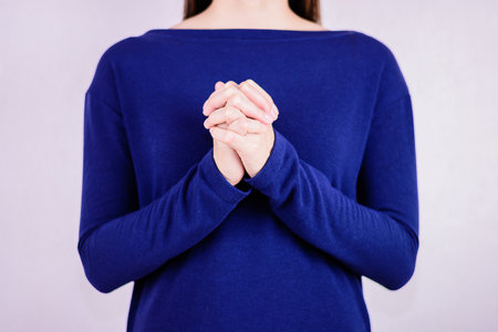 Woman in blue dress begging and praying with hands together with blur backgroundselective focus at hands.の写真素材