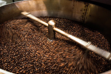 fresh coffee beans roasted spinning cover professional machine close up to soft focus  slow shutter speed because want to make motion blur of coffee beans detail concept, at factory chiang rai Thailand, angle view shot.の写真素材