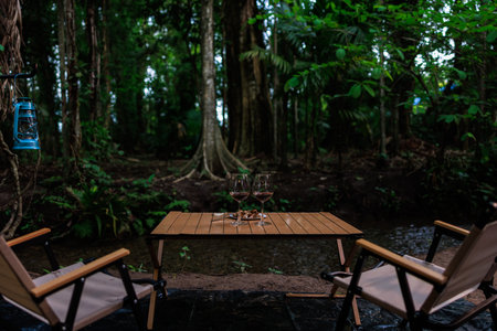 2 Wine glasses on the table in camping nature at twilight. by the stream.