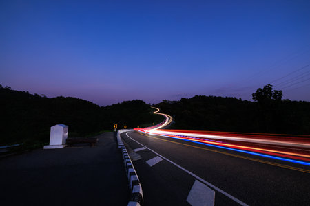 Photograph long exposure shot car light, twilight time blue sky background, at Curved Road No.3 or Route No.1081 over top of mountains in Santisuk - Bo Kluea District, Nan province, Thailandの写真素材