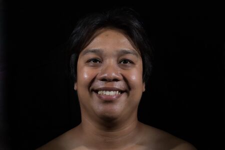 Portrait of a man smiling with in studio black backgroundの写真素材