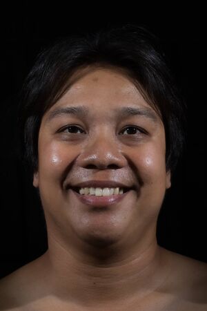 Portrait of a man smiling with in studio black backgroundの写真素材