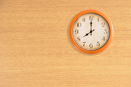 Clock showing 8 o'clock on a wooden wallの写真素材