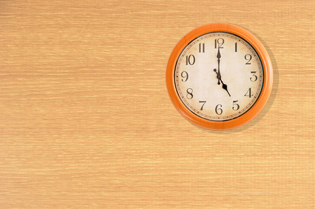 Clock showing 5 o'clock on a wooden wallの写真素材