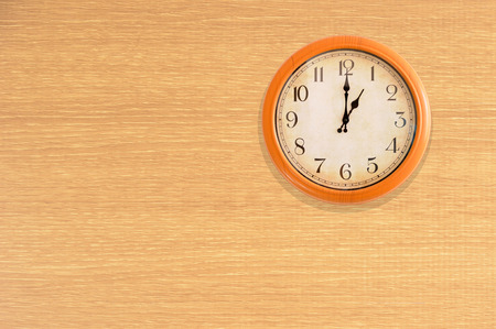 Clock showing 1 o'clock on a wooden wallの写真素材