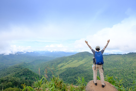 Rear view of man stretching arms on cliff at Phu-Soi-Dao National Park, Utradit, Thailandの写真素材