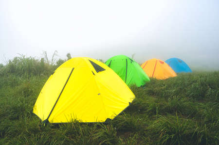 Trekking tents on green grass in the mist at Doi Suan Ya Luang, Ban San Charoen district, Nan province, Thailandの写真素材