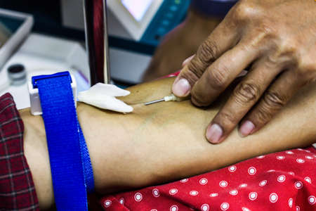 Cropped image of doctor drawing blood from male patient's arm in examination room