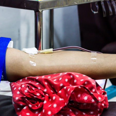 Cropped image of doctor drawing blood from male patient's arm in examination roomの写真素材