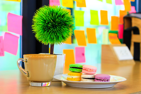 A batch of coloroful French macaroons on a table and Coffee, cappuccinoの写真素材
