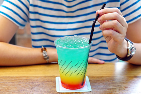 Colorful Cocktail or Tropical Mocktail - Plastic glass of Energy Drink with lemonade, orange juice and watermelon syrup on wooden table.の写真素材