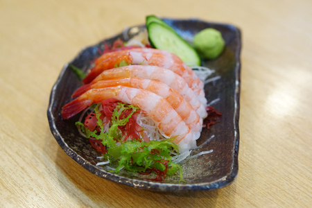 Fresh Amaebi (Sweet Shrimp) Sashimi Set served with wasabi, zucchini seaweed and grated radish on plate.の写真素材