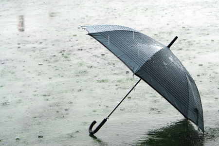 Umbrella on rainy day - The raindrops falling on an umbrella which put on the ground, make me so lonely.の写真素材
