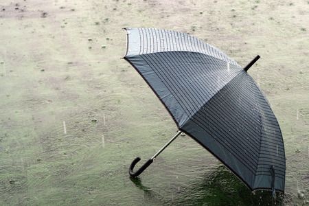 Umbrella on rainy day - The raindrops falling on an umbrella which put on the ground, make me so lonely.の写真素材
