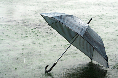 Umbrella on rainy day - The raindrops falling on an umbrella which put on the ground, make me so lonely.の写真素材