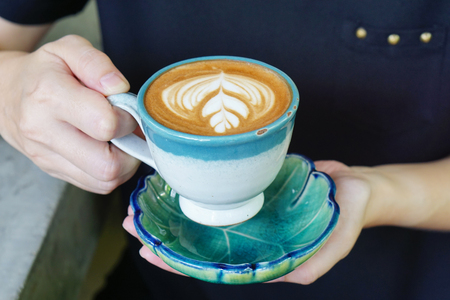 Hot Mocha - Woman holding a cup of coffee with beautiful latte art, Morning breakfast.の写真素材