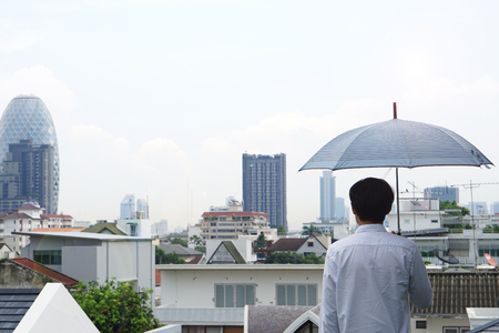 After heavy rain, A man holding an umbrella waiting for someone in the city.の写真素材