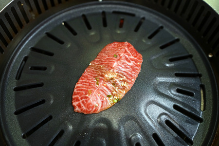 Wagyu flat iron - Grilling raw thin sliced beef on the hot charcoal stove, Japanese barbecue style also know as Yakiniku.の写真素材