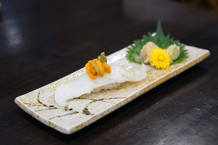 Aburi engawa sushi - Grilled flatfish (Fluke fin) on rice topping with fresh uni served with pickled ginger, Japanese traditional food.の写真素材