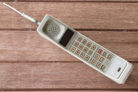 vintage mobile phone on brown wood background.の写真素材