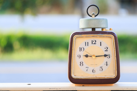 Retro alarm clock on table on nature background