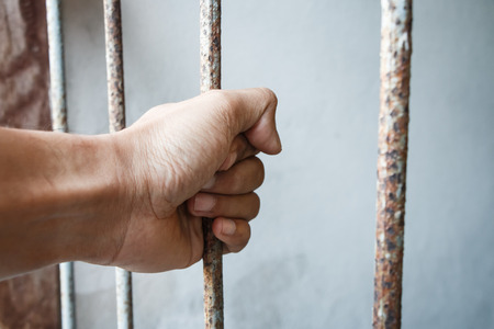 hand of jail holding prison barsの写真素材