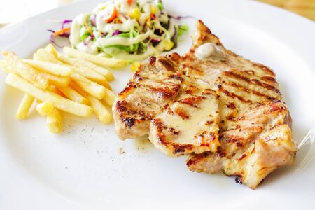 Grilled pork steak with french fries and saladの写真素材