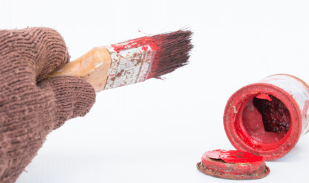 hand glove holding paint brush and red paint on white backgroundの写真素材