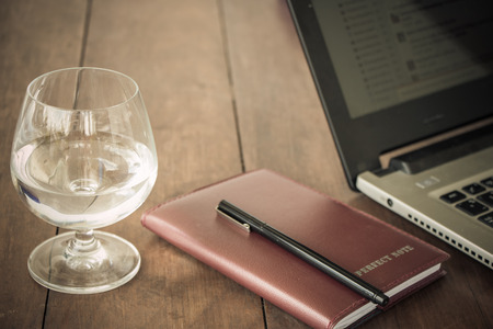 Glass and book and laptop on deskの写真素材