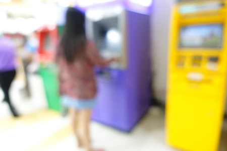 Blurred image of woman use ATM machine in bank to take money or do something about financial.の写真素材