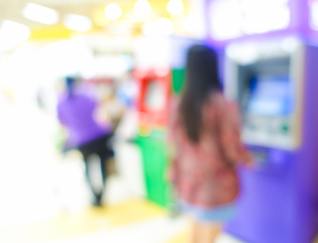 Blurred image of woman use ATM machine in bank to take money or do something about financial.の写真素材