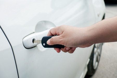woman hand holding car keys to unlock or lock the white carの写真素材