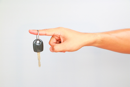 Male hand holding car key isolated on white backgroundの写真素材