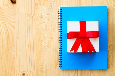 Gift box with red wrapped and blank paper put on wooden tableの写真素材