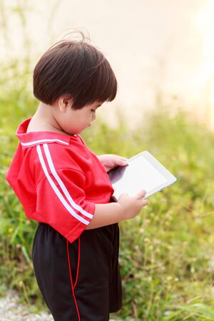Cute kid holding tablet computer to learn or play game, education concept.の写真素材