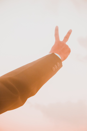 Silhouette of business man hand show two fingers at sunset background
