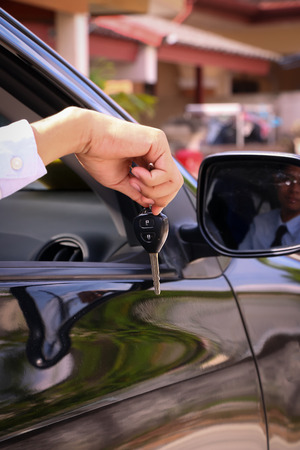 Business man  showing key and sit in carの写真素材