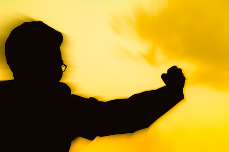 Motion silhouette of man showing his hand on golden sunset sky background, Successful business concept.の写真素材