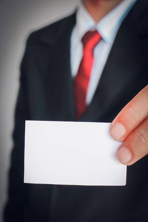 Businessman showing paper on gray background,Vintage tone style.の写真素材