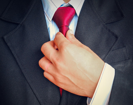 Portrait of business man in suit holding red tie on gray background, Vintage tone style.