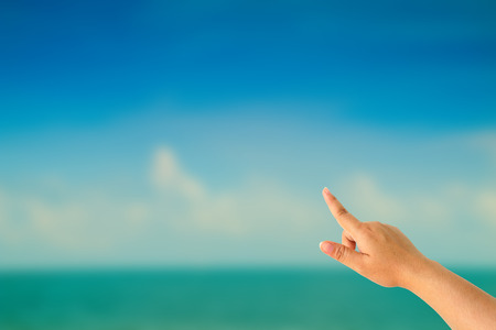 Female hand against a beautiful blue sky pointing somewhereの写真素材