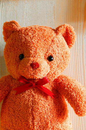 Bear doll put with red bow put on wooden table.の写真素材