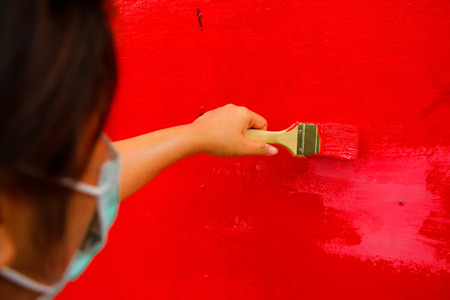 woman artist use brush with red color on wall.の写真素材