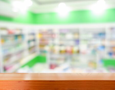 Brown wooden tabletop with blurred pharmacy or medicine shelf at the hospitalの写真素材