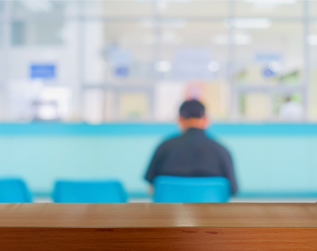 Wooden tabletop under blurred of picture people or patients in hospital waiting doctor or medicine.の写真素材