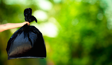 human hand showing garbage bag on fresh green nature blurred background, recycle conceptの写真素材