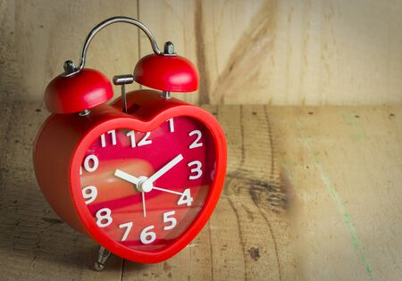 Red alarm bell on old wooden texture background mark at 10.00 o'clock