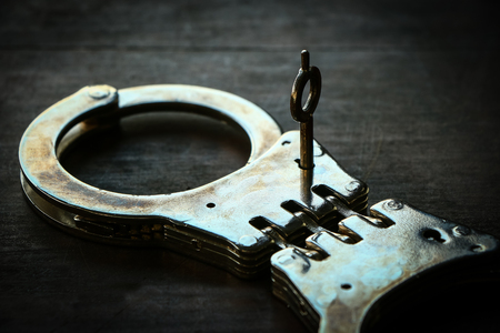 Handcuffs on old wooden table backgroundの写真素材