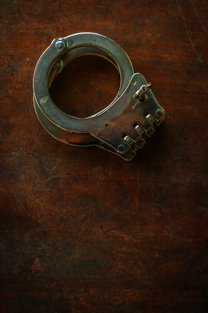 Handcuffs on old wooden table backgroundの写真素材