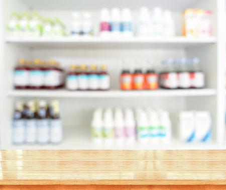 Brown wooden tabletop with blurred pharmacy or medicine shelf at the hospitalの写真素材